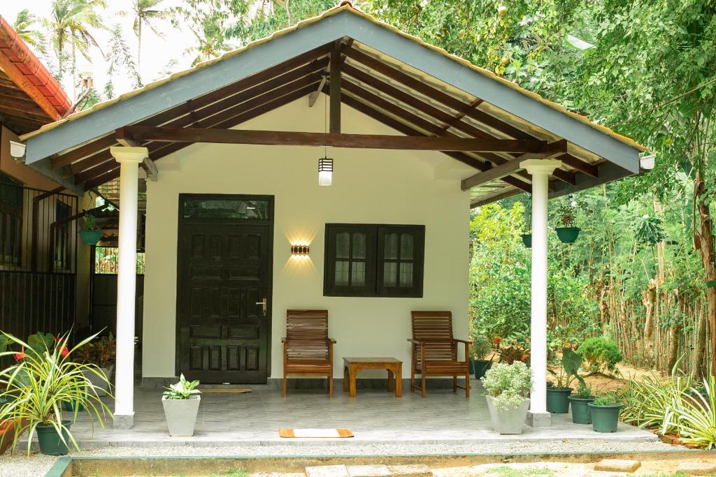 a pavilion with chairs and a table in front of a house at The Hollyoak - Vintage Charm with Modern Comforts in Denipitiya