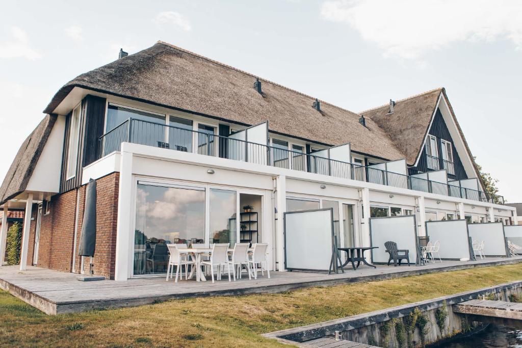 a house with a deck with tables and chairs at Herenhuis geschakeld | 8 personen - Boutique Parc Pharshoeke in Heeg