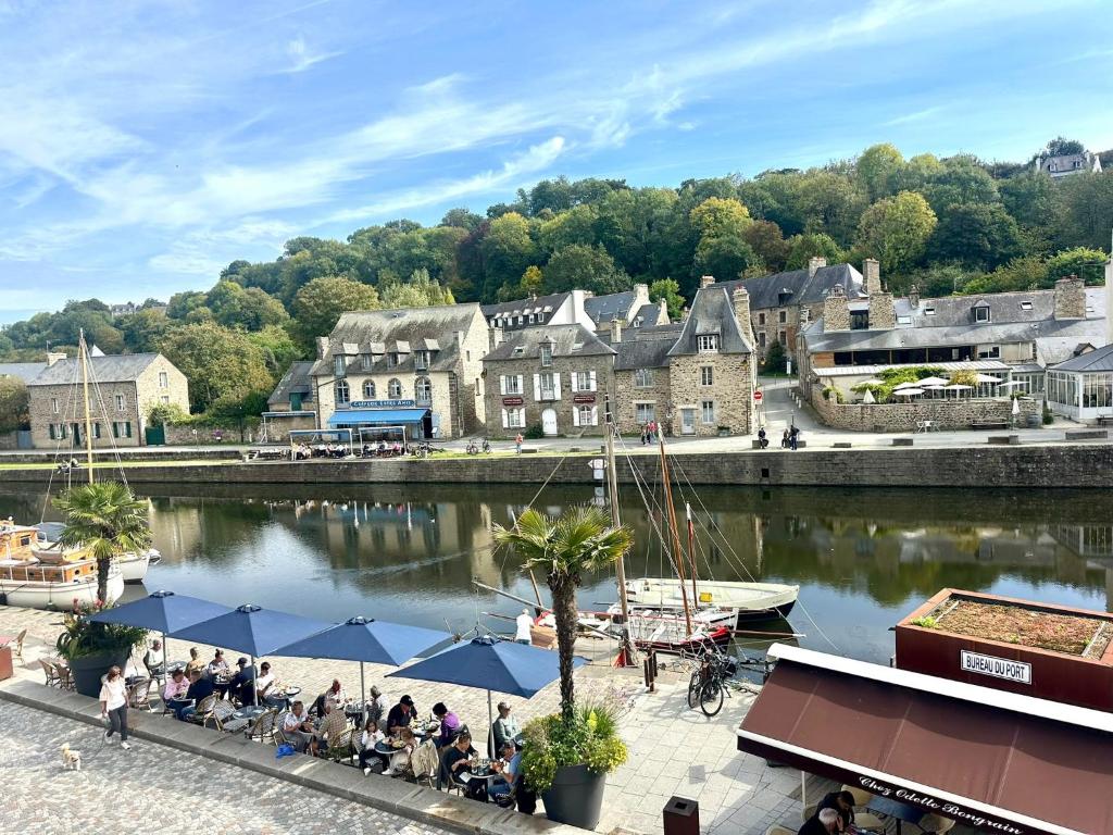 a group of people sitting at tables by a river at Appartement au port de Dinan Belle île in Dinan