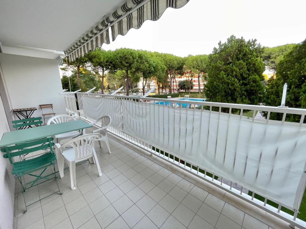 a balcony with a table and chairs and a pool at Welcoming flat with pool view balcony in Porto Santa Margherita di Caorle