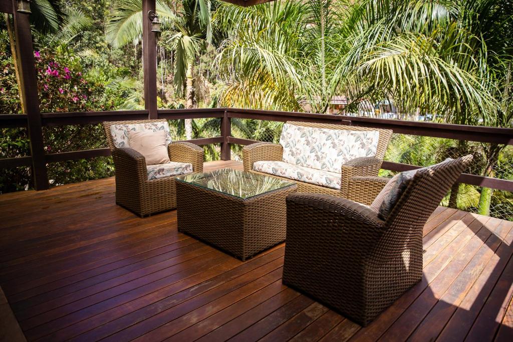Un patio con sillas de mimbre y una mesa de vidrio en una terraza. en Chale com lazer completo nas Montanhas, en Vítor Hugo