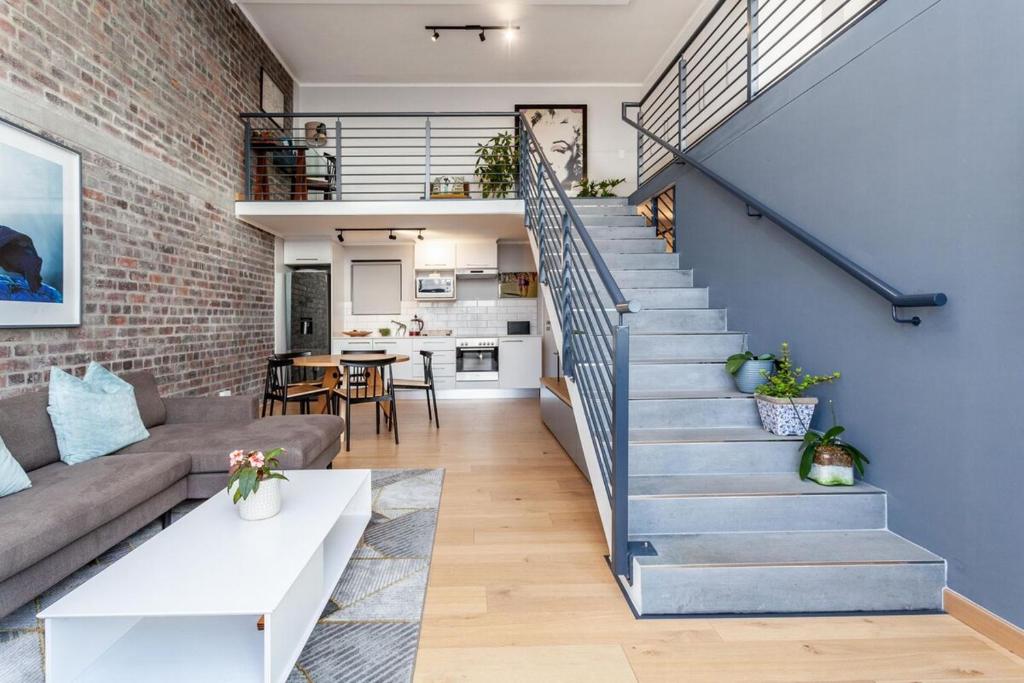 un soggiorno con scala e muro di mattoni di Stylish Cape Town Penthouse a Città del Capo