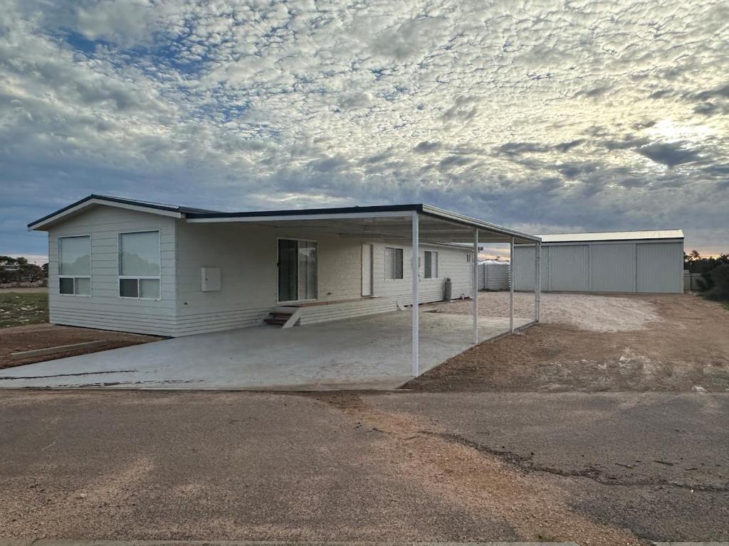 a small white house with a large driveway at Newly Renovated Coastal Retreat in Port Kenny