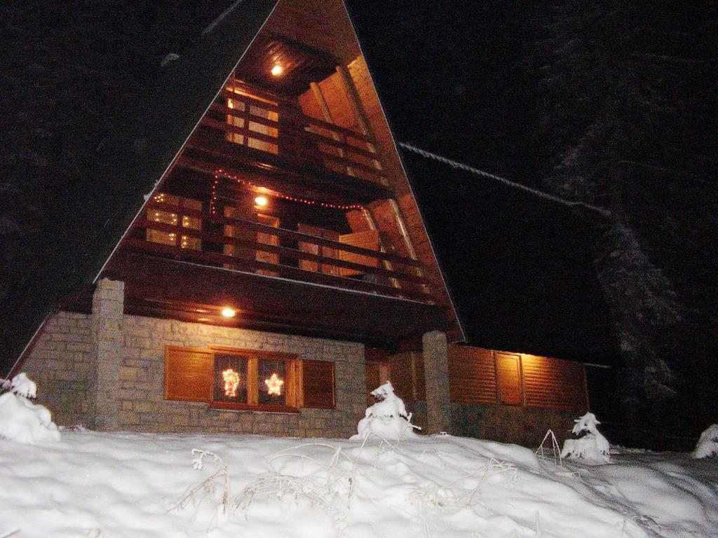 a building at night with snow in front of it at Vikendica Luna in Gornja Šišava