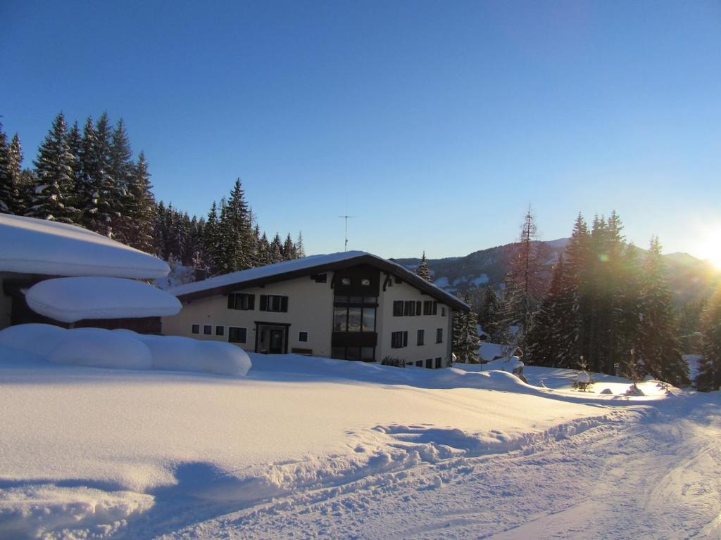 a house covered in snow with the sun behind it at Hochkönig Top 6 - Ski in-out in Mühlbach am Hochkönig