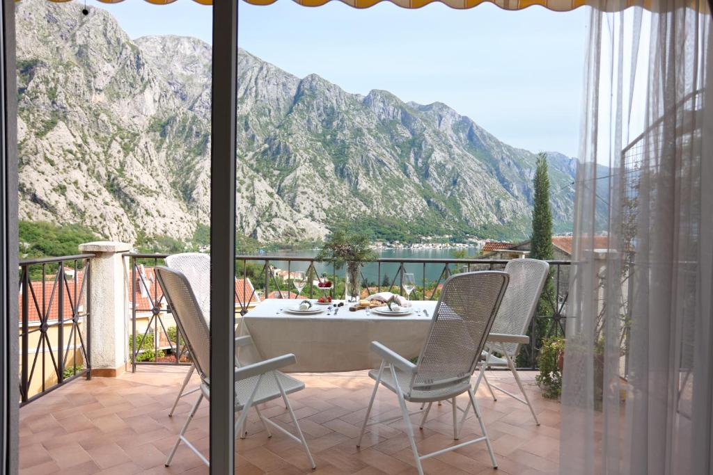 a table and chairs on a balcony with mountains at Boka Kotorska Apartmani in Gornji Orahovac