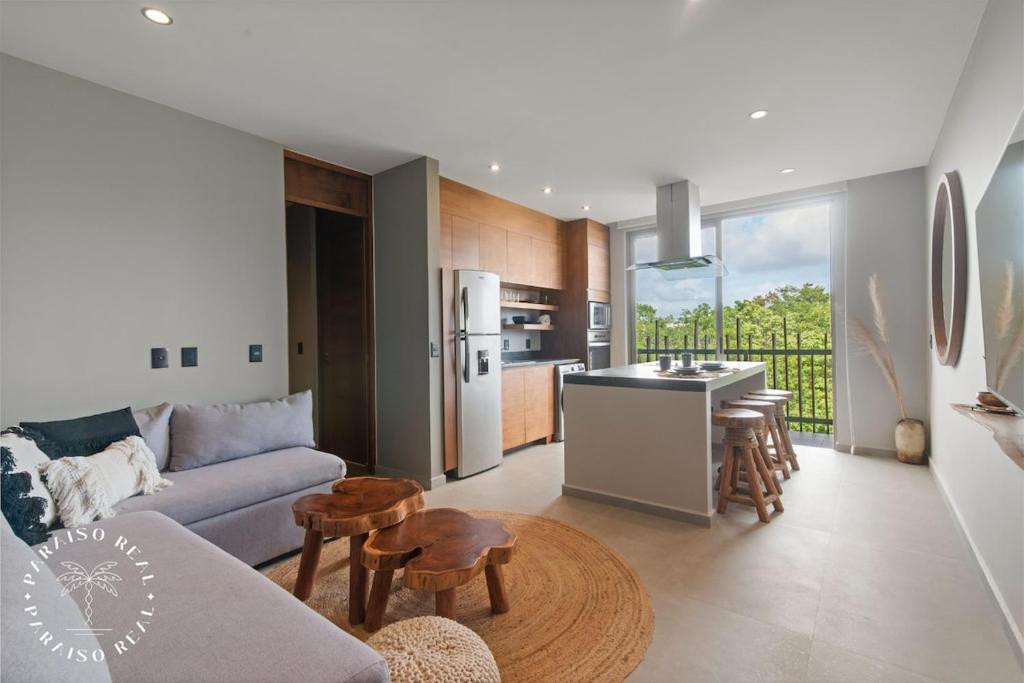 Una sala de estar con un sofá y una cocina. en Boho Chic 1Bdr Pool and Spa, en Tulum