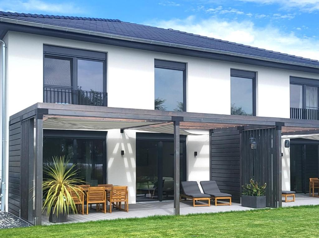 a white house with black windows and a patio at Ferienhaus Schlossterrassen 8b in Pouch