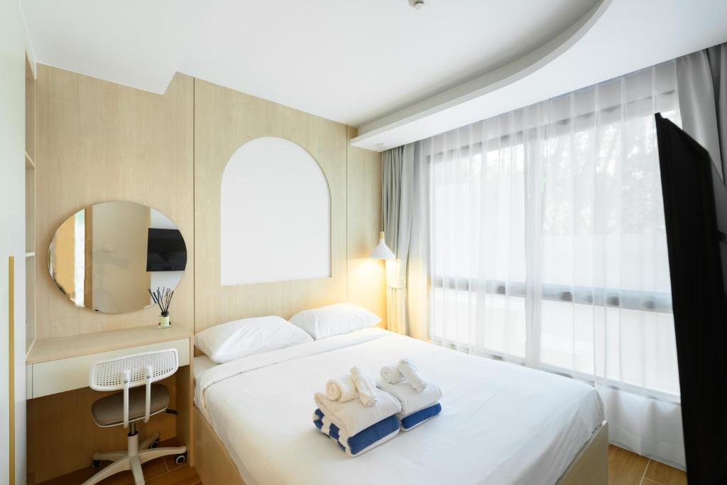 a bedroom with a bed and a desk and a window at Fantasea Condo Kamala B211 2BDRM by Phuket Sabay Rent in Kamala Beach