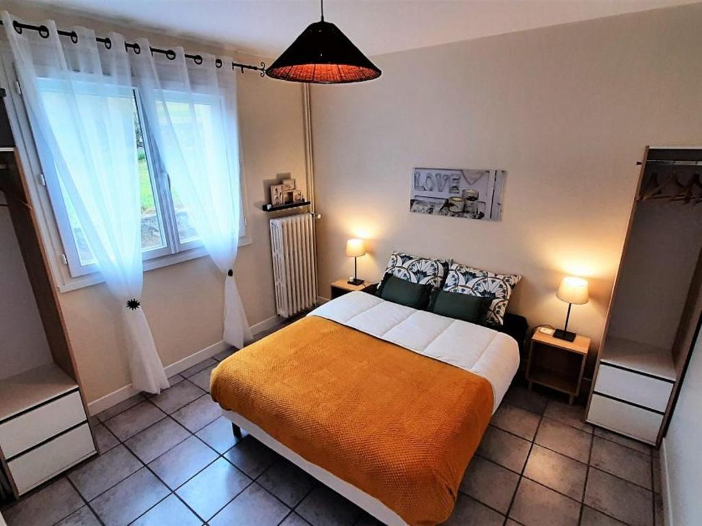 una camera con un grande letto e due finestre di Gîte "Le temps d'une pause" terrasse et piscine a Coubon