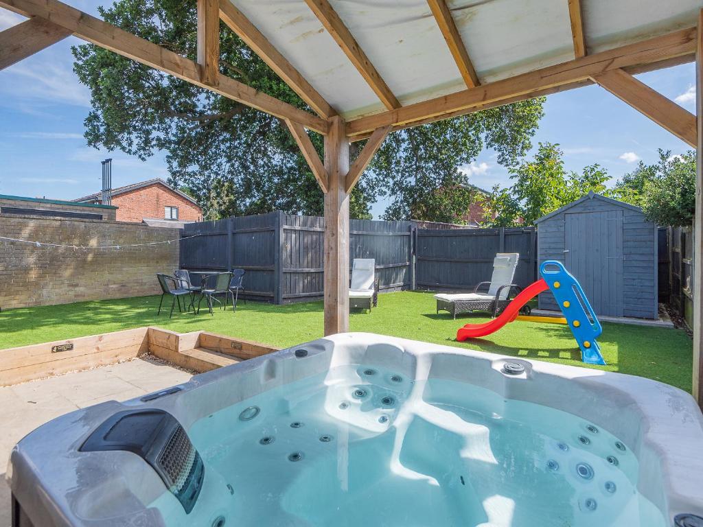 a hot tub in a backyard with a playground at Goose Green Cottage in Snettisham