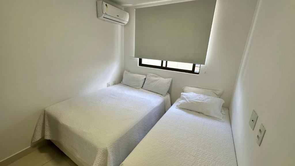 two beds in a small room with a window at Apto Novo PraiaTambaúCabo Branco in João Pessoa
