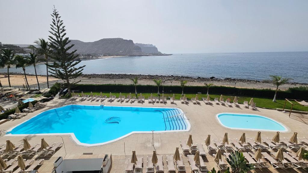 a swimming pool with chairs and a view of the ocean at Cura Marina Premium in Mogán
