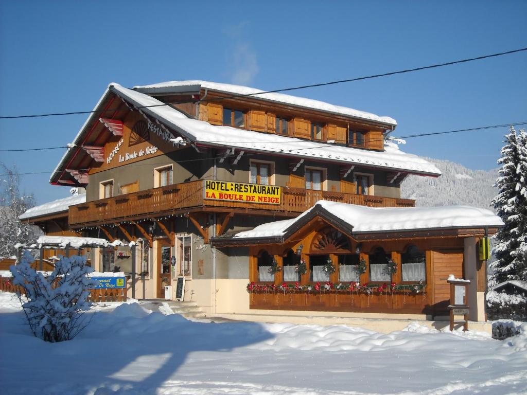 a large wooden building with snow on the ground at La Boule de Neige in Samoëns