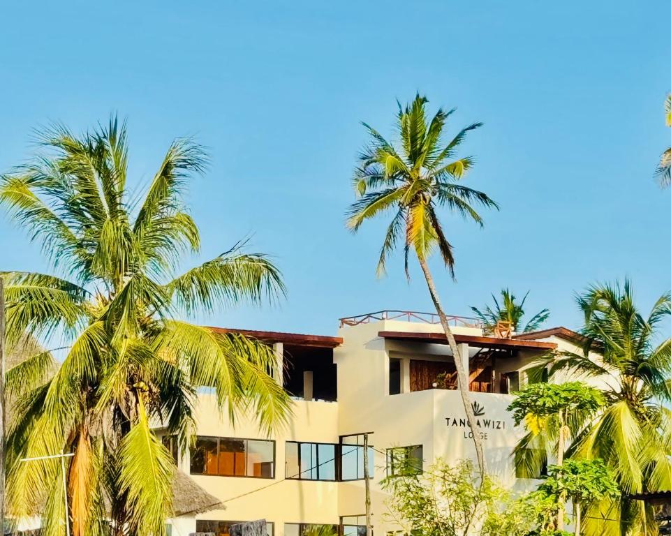 a hotel with palm trees in front of it at Tangawizi Lodge Zanzibar - Adults Only in Jambiani