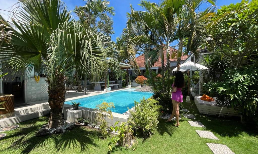 Una mujer está de pie junto a una piscina. en Lila Boutik Residence, en Canggu