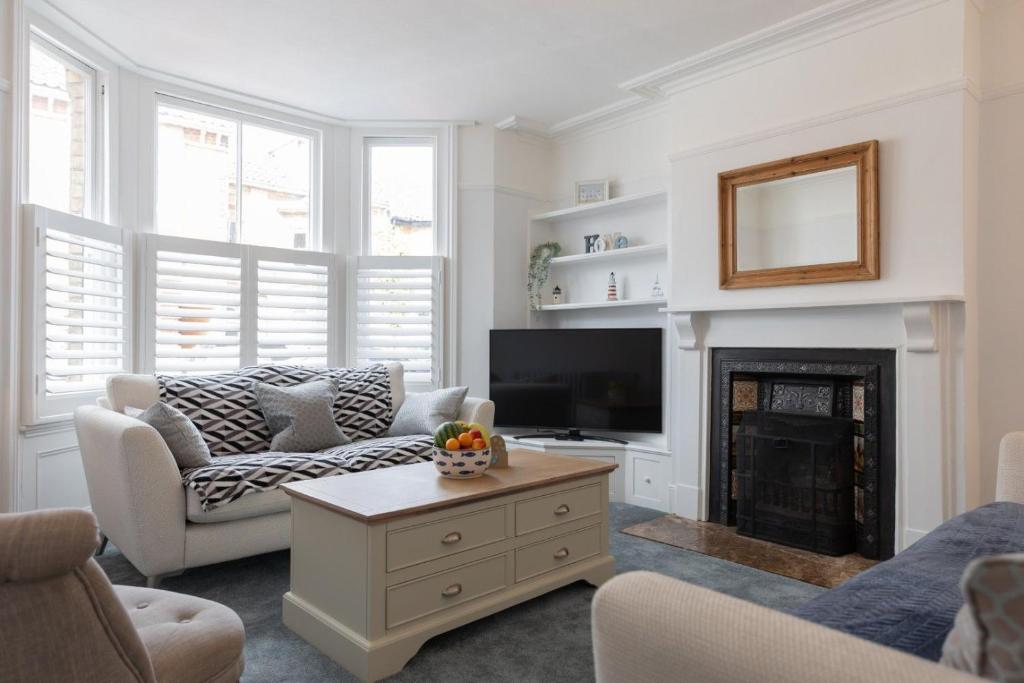 a living room with a couch and a fireplace at Sole Rose in Southwold