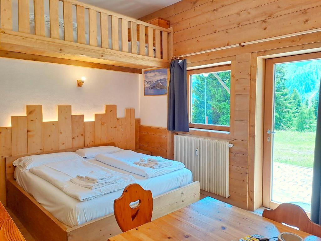 a bedroom with a bed in a wooden house at Valles Vacanze - ski in & ski out in Falcade