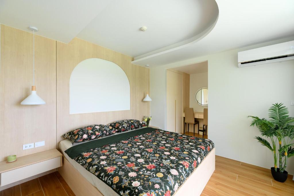 a bedroom with a large bed with a floral blanket at Fantasea Condo Kamala B708 1BDRM by Phuket Sabay Rent in Kamala Beach