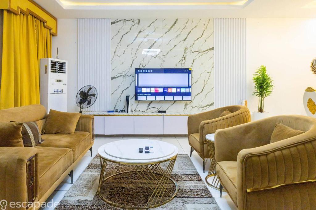 Una sala de estar con sofás marrones y un televisor. en Luxurious Abuja Apartment with Modern Amenities, en Jabi