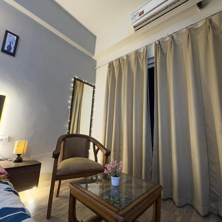 a living room with a table and a chair and a window at The Chill Spot in Greater Noida