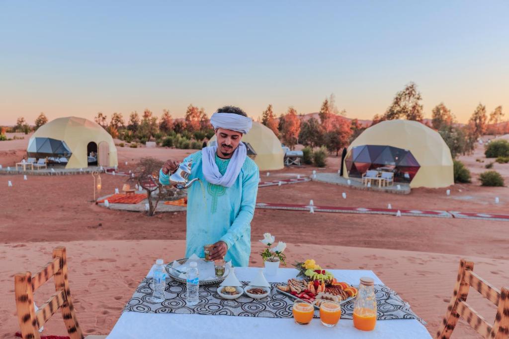 un hombre parado frente a una mesa con comida en Desert Dream Apartment, en Merzouga