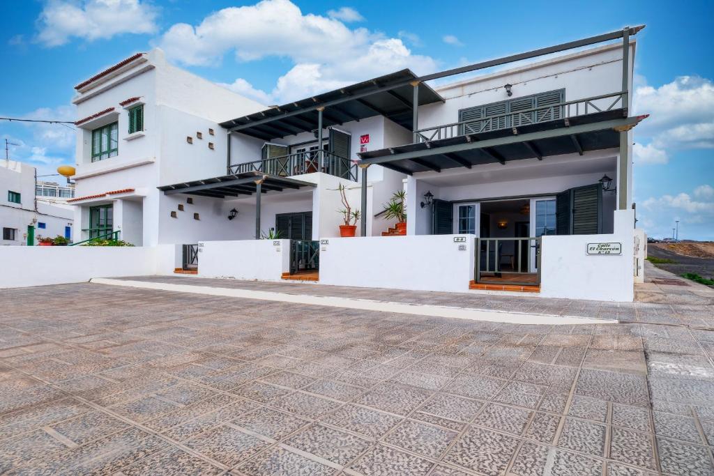 a white house with a courtyard in front of it at Apartamento El Charcon B - 10 meters to the Beach By Lanzarote Vacation Homes in Arrieta