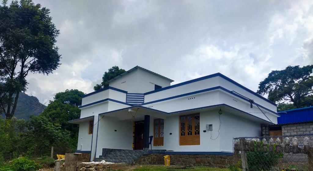 a white house with a blue roof at Munnar Wood valley in Munnar