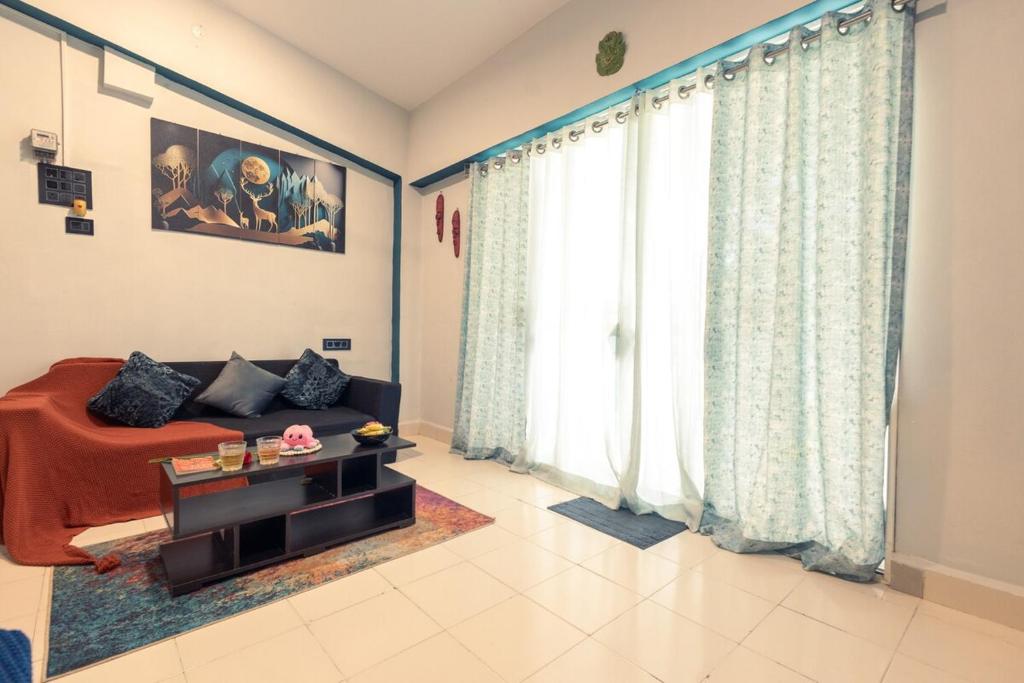 アーポラにあるSpacious 1BHK WiFi Balcony and Pool View near Anjunaのソファと大きな窓のあるリビングルーム