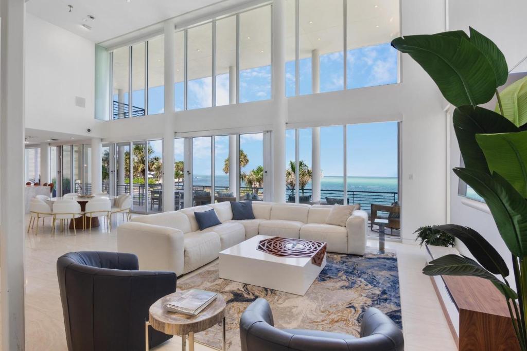 Una sala de estar con muebles blancos y grandes ventanales. en Siesta Sunset Sanctuary, en Bailey Hall