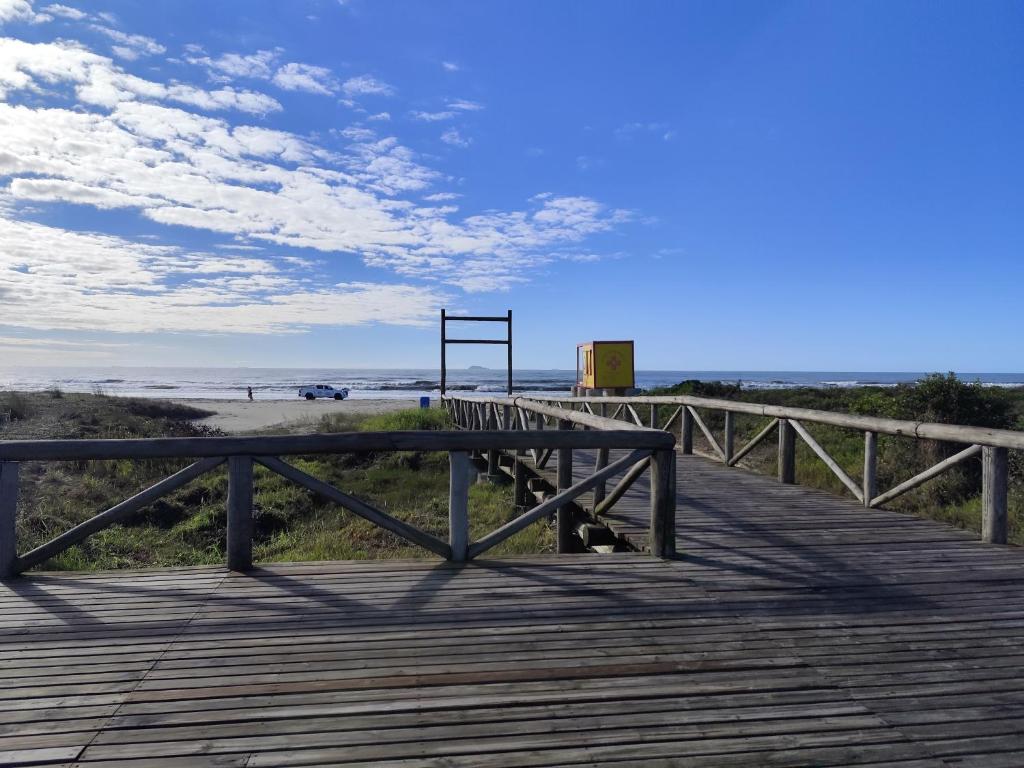 un paseo marítimo de madera que conduce a una playa con un banco en Apartamento 21 Praia de Leste, en Pontal do Paraná