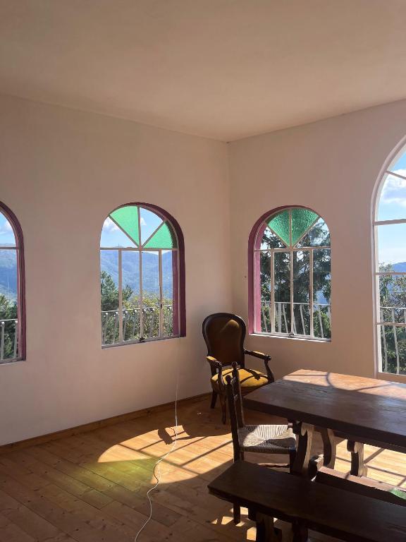 a room with three windows and a table and chairs at Humus Sapiens 2 in Tavarone
