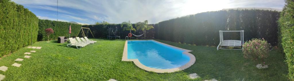 a swimming pool in a yard with two chairs and a swing at Casas do Maranhão Póvoa de Varzim in Navais