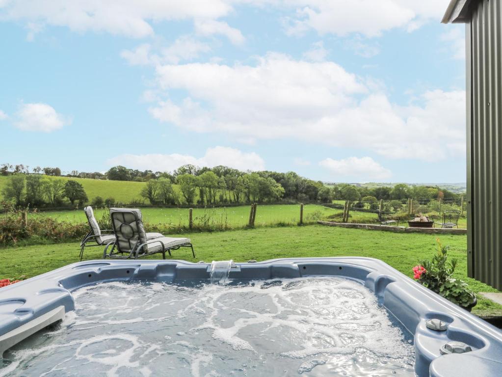 a hot tub in a yard with two chairs at Brondel Luxury Shepherd's Hut in Aberystwyth