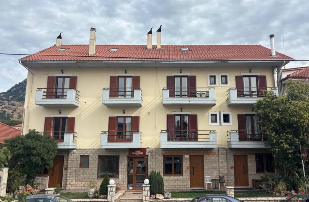 a large yellow building with red windows and balconies at Tzovolos Apartments in Kalavrita