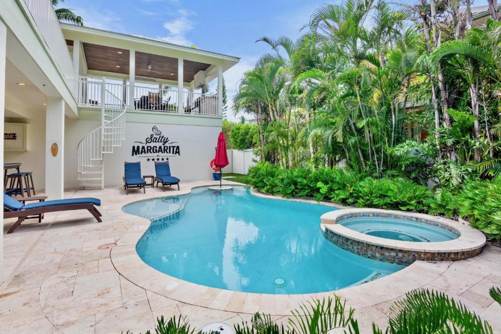 a swimming pool in the middle of a patio with chairs and trees at Salty Margarita in Anna Maria Island