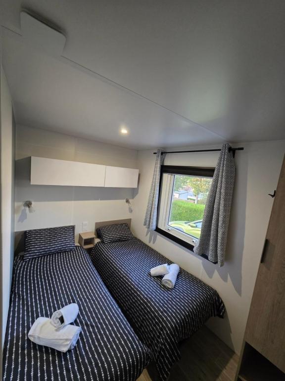 two beds in a small room with a window at Houlgate-206- Mobilhome Premium 6 personnes Camping 5 étoiles - Séjour Normandie - Paris Eure Gestion in Houlgate