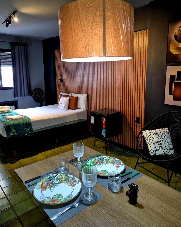 a room with a bed and two plates on a table at Studio Quartzo verde, Centro. in Campos dos Goytacazes
