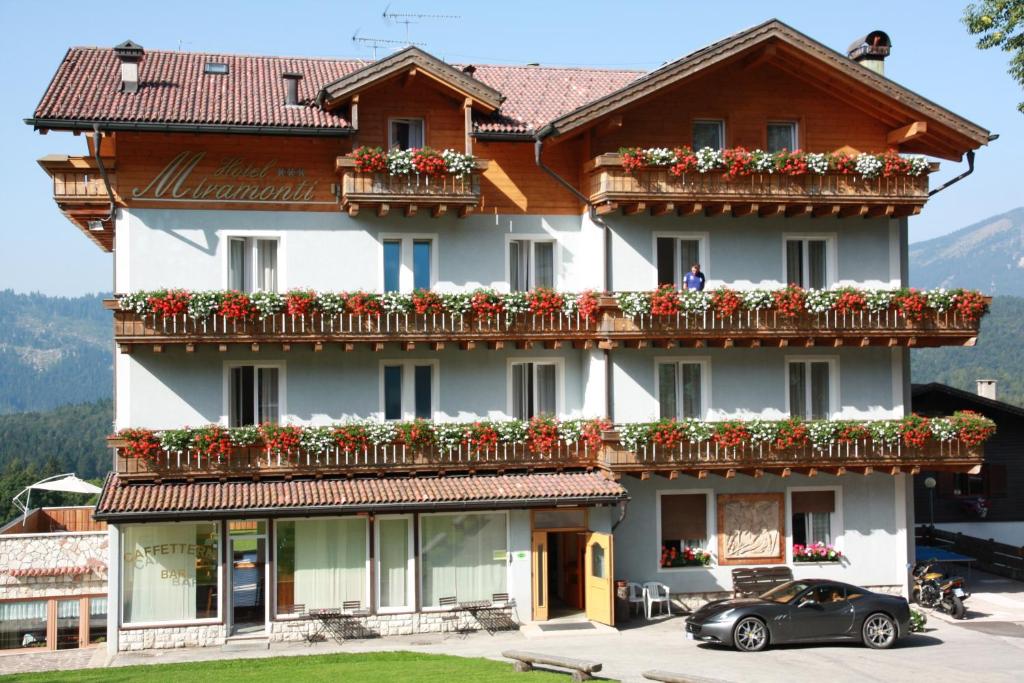 un grand bâtiment avec des fleurs sur les balcons dans l'établissement Albergo Miramonti, à Lavarone