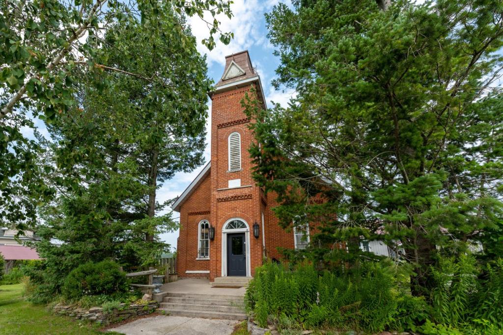 a red brick church with a clock tower at The Prince Edward County Church, A Unique Escape in Belleville