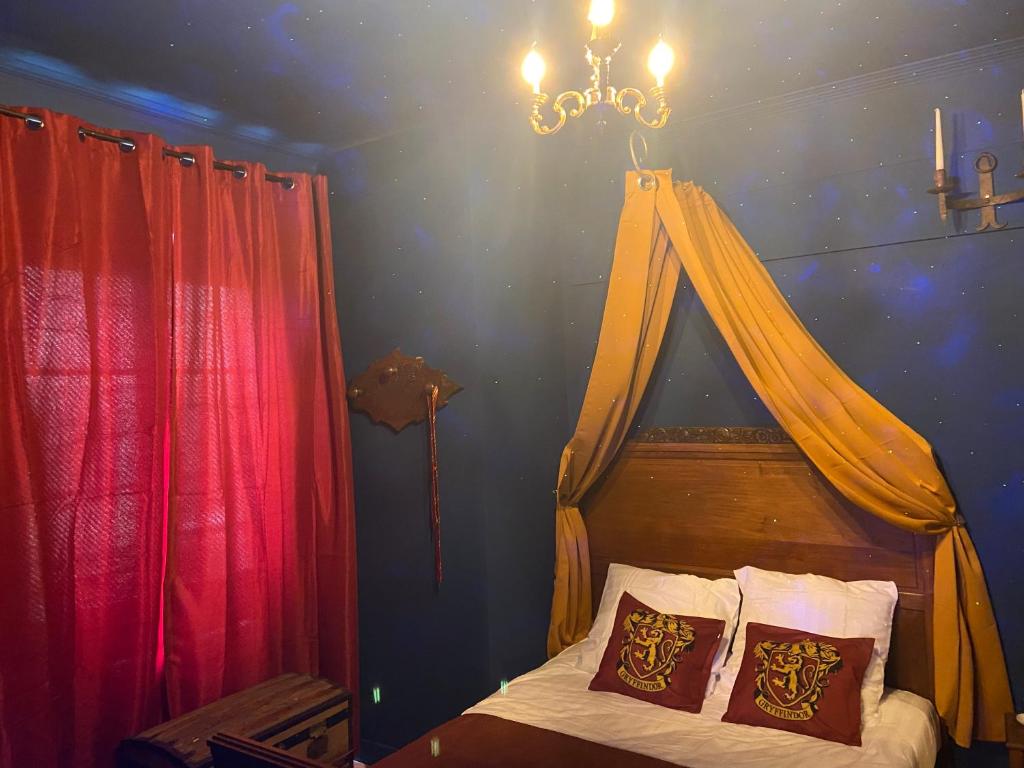 Un dormitorio con una cama con dosel y una lámpara de araña. en Le refuge des Mans-raudeurs, en Le Mans