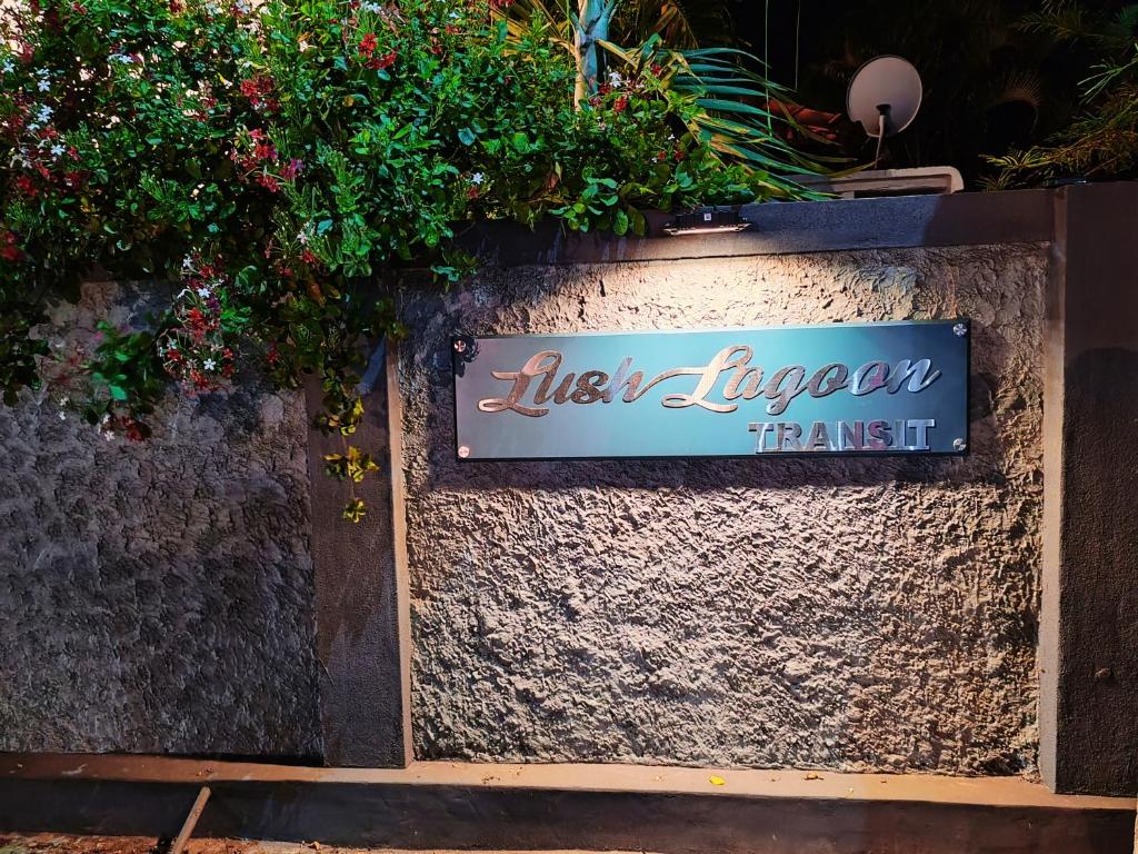 a sign for a restaurant on a wall with flowers at Lush Lagoon Transit Katunayake in Katunayake