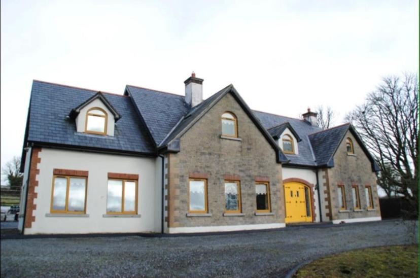a large brick house with a yellow garage at The Mansion in Ballintober