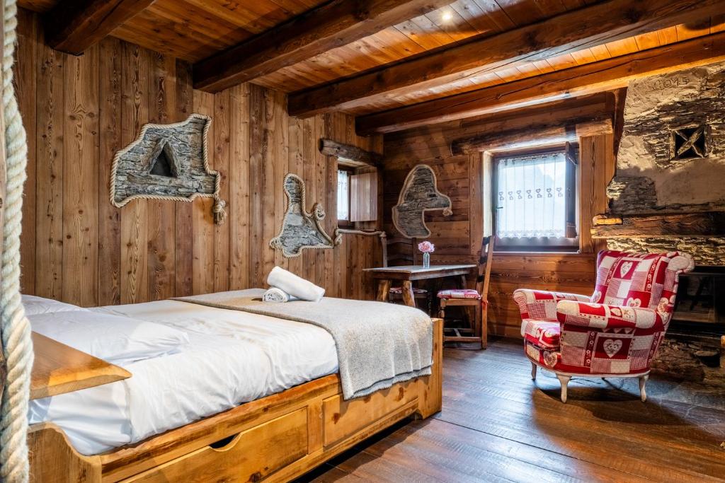 um quarto com uma cama e uma cadeira em um cômodo em Brieis Relais Alpino em Marmora
