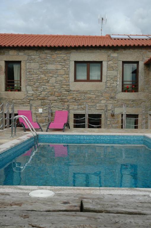 twee roze stoelen naast een zwembad bij Casa de l Telar in Duas Igrejas