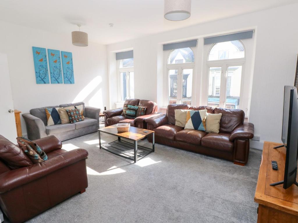 a living room with leather couches and a tv at Castleview Coastal Comfort in Oystermouth