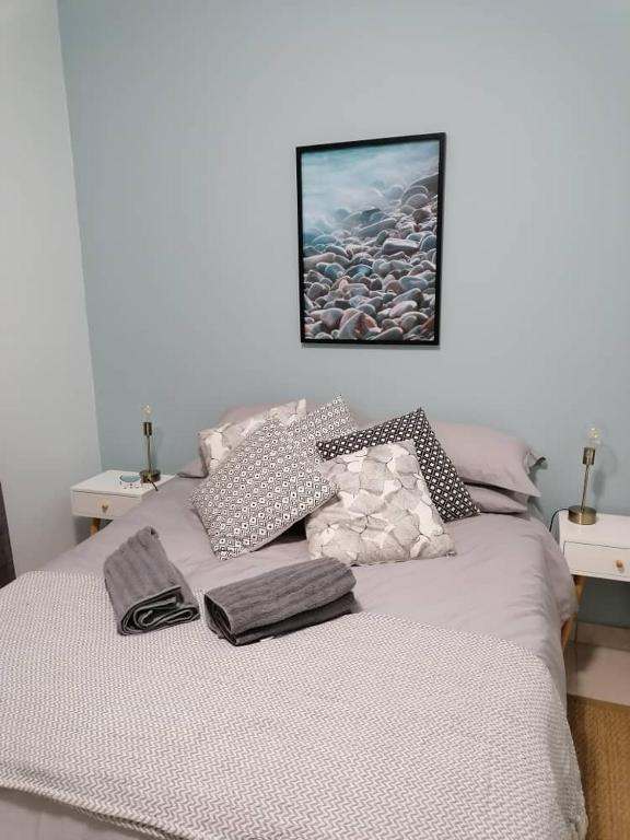 a bed with pillows and a picture on the wall at The Pebble Garden Swakopmund in Swakopmund