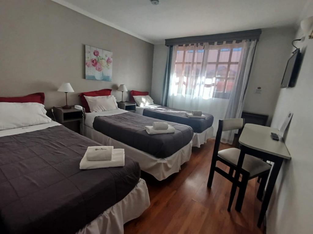 a hotel room with two beds and a desk and a chair at Hostal malvinas in Ushuaia