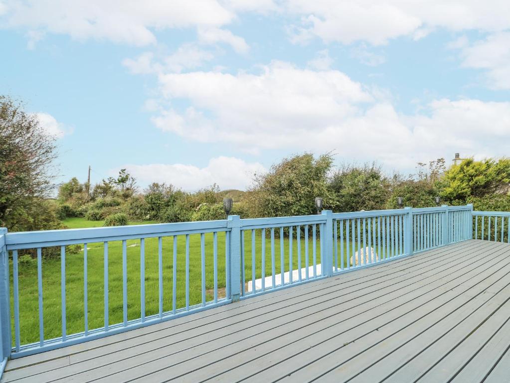 a wooden deck with a blue fence and a field at Harbour Lights in Holyhead