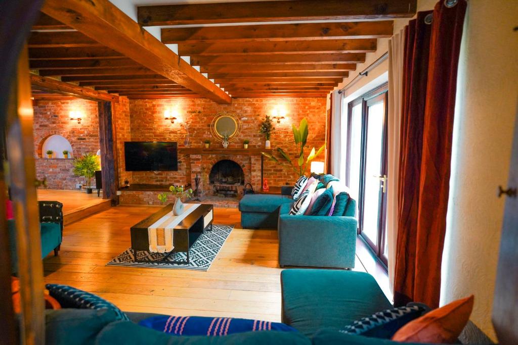 ein Wohnzimmer mit blauen Sofas und einem Kamin in der Unterkunft Bright & Spacious 5-Bedroom Stay near Cambridge in Hardwick